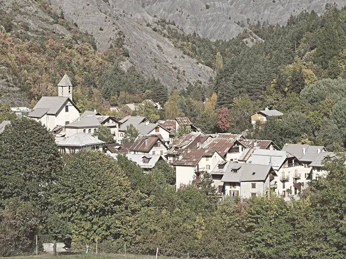 Vue automnale du village d’Entraunes depuis un grand pré au sud-ouest